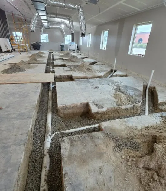 New drain line in a saw-cut slab trench during a renovation