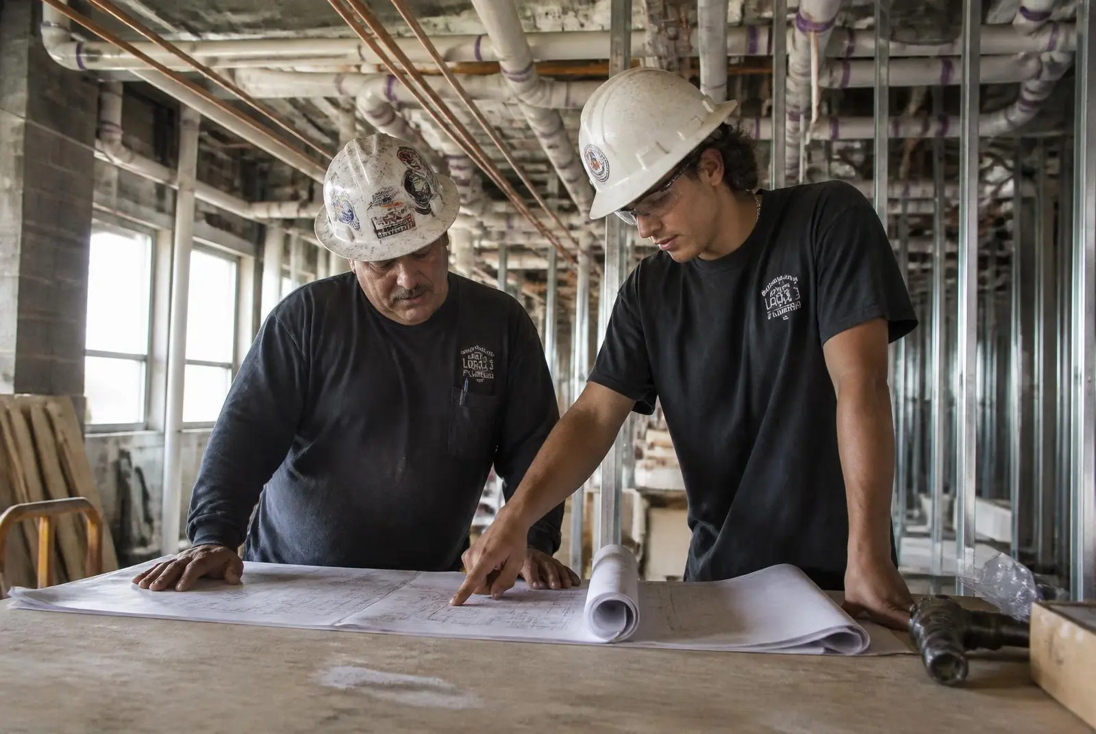 Legacy Plumbing foreman reviewing project plans with an apprentice on a St. Louis commercial jobsite